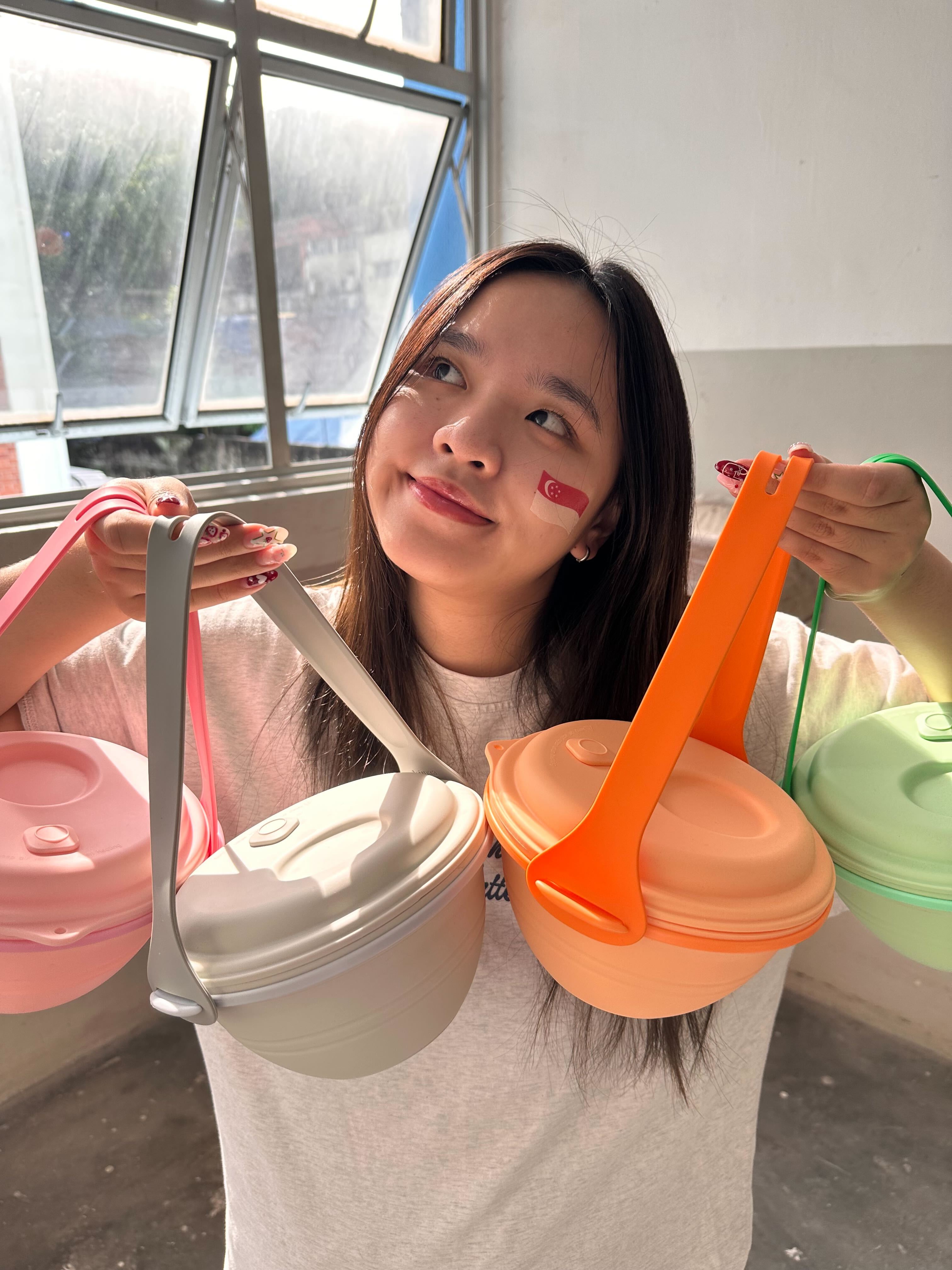 Person holding colorful silicone containers with lids in a kitchen setting