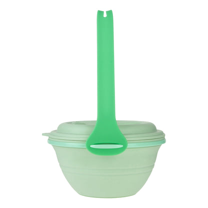 Green lunch box uncollapsed with the strap hooked onto it, side view.